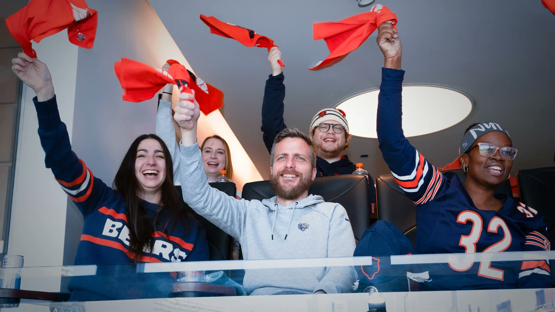 Guests in a stadium suite waving rally towels and cheering