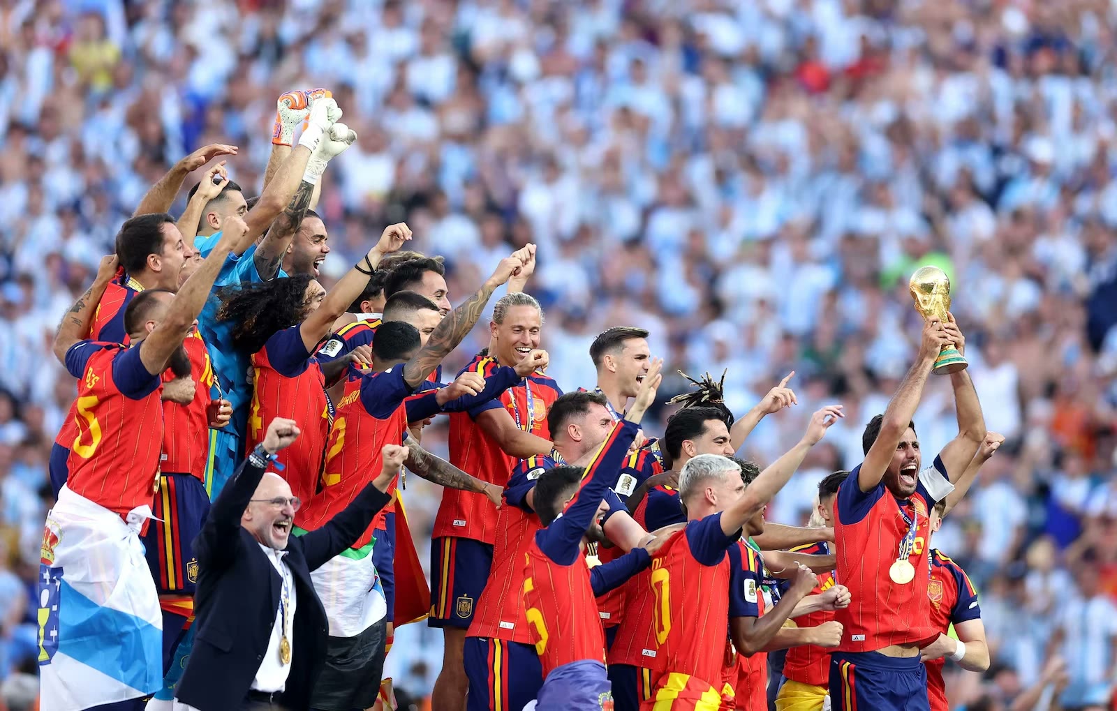 Players celebrating with the World Cup trophy in front of a packed stadium