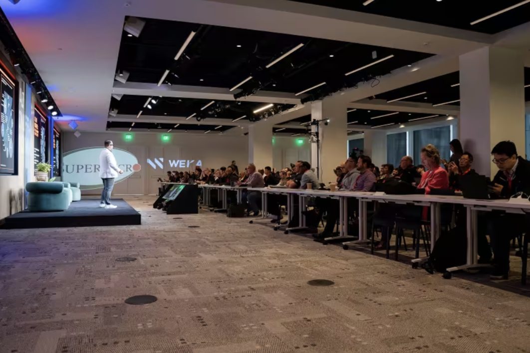 Executive session room with long tables and a presenter on stage
