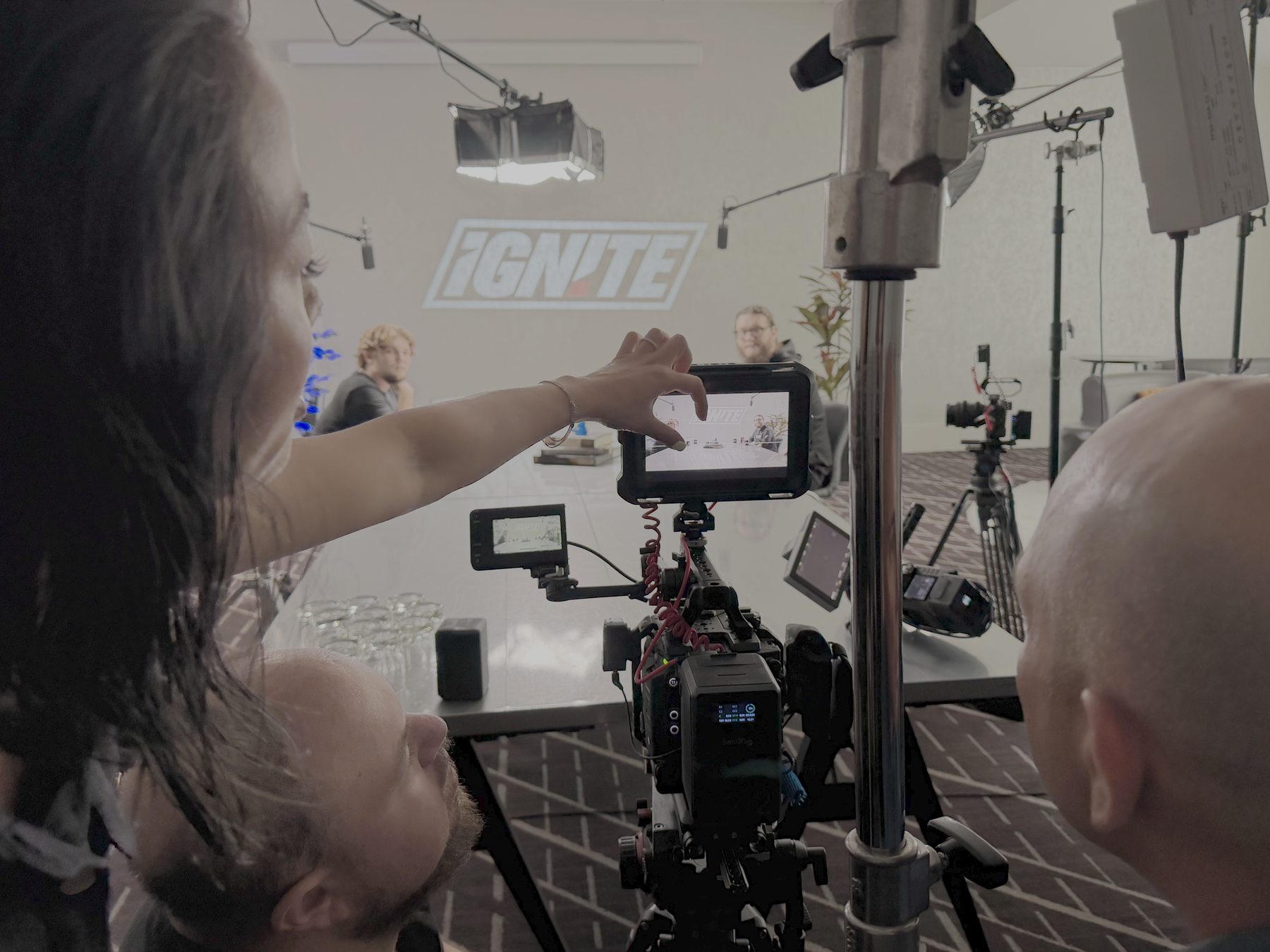 An Ignite Studio director adjusts the field monitor while a two-camera interview films in front of the IGN!TE wall